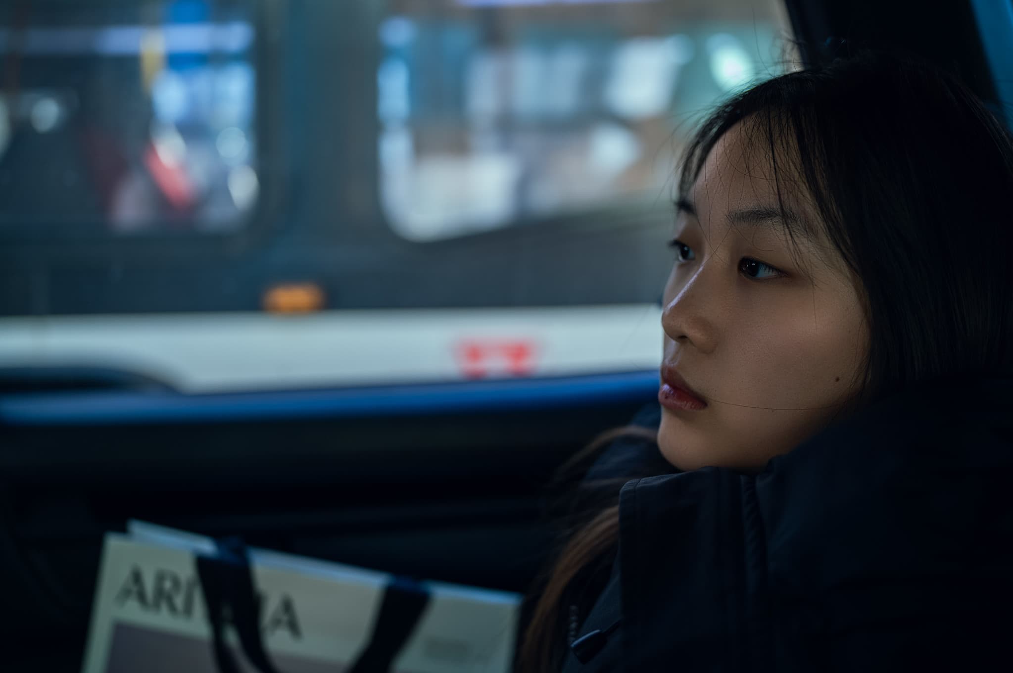 A cinematic portrait of a young woman near public transit.